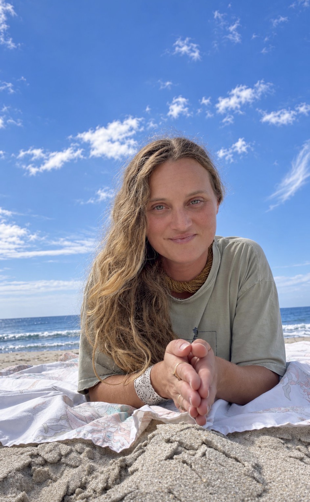 Kir lying on the sand at the beach, smiling under a blue sky